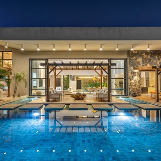 Modern luxury villa with stunning pool reflecting the contemporary architecture under evening sky.