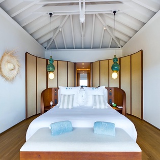 Drift off under soaring vaulted ceilings in your serene bedroom, where turquoise pendant lights and warm wood create the perfect tropical sanctuary.