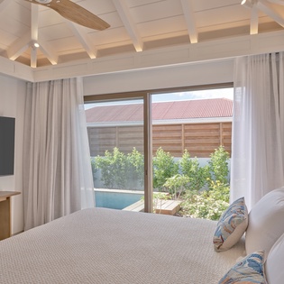 Wake up in your serene bedroom with pool views and elegant exposed ceiling beams creating the perfect retreat.