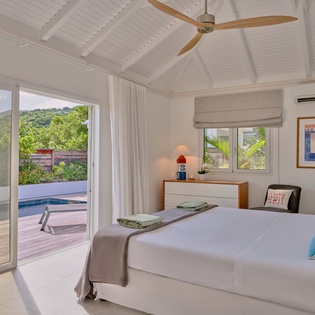 Your bright bedroom opens to a private pool deck, where tropical breezes flow through floor-to-ceiling windows and vaulted ceilings create an airy retreat.