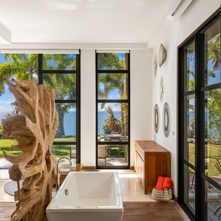 Soak in your private tub surrounded by floor-to-ceiling windows showcasing tropical palms and ocean views.