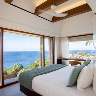 Wake up to breathtaking ocean views from your luxurious bedroom, where warm wood beams frame endless blue horizons.