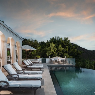 The property sits majestically atop lush hillsides, framed by a serene sunset sky, offering a stunning backdrop to this private paradise in the tropics.