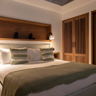 Sink into plush linens and warm wood accents in your serene bedroom retreat, where thoughtful lighting creates the perfect ambiance for rest.