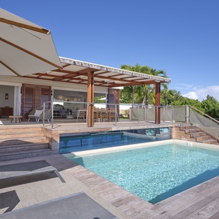 Stunning modern villa featuring a pristine swimming pool surrounded by elegant wooden decking and tropical greenery.