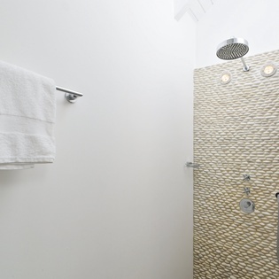 Step into your spa-inspired shower with natural stone textures and rainfall head, where fluffy towels await your refreshing escape.