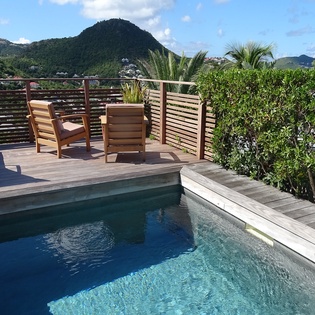Your private pool deck overlooks lush mountains, where teak loungers invite afternoon relaxation amid tropical garden privacy.