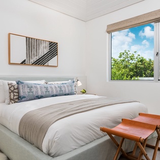 Rest peacefully in your bright bedroom with garden views through large windows and crisp white linens awaiting your arrival.