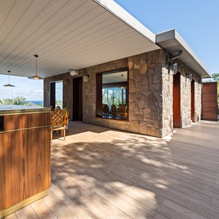 Modern stone and wood villa with ocean views, surrounded by tropical landscaping and contemporary design.