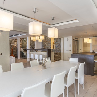 Gather around a spacious modern dining table, where warm pendant lighting sets the tone for memorable meals with your group. The open layout flows seamlessly into a sleek kitchen, making it easy to share food, conversation, and laughter.