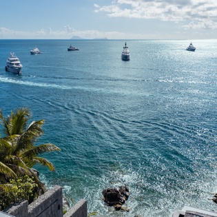Stunning oceanfront location with crystal-clear waters and luxury yachts dotting the sparkling turquoise bay beneath tropical palms.