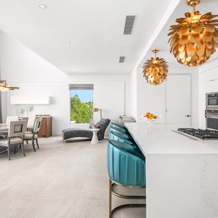 Your gourmet kitchen flows seamlessly into elegant dining and living spaces, where striking golden pendant lights illuminate gatherings.