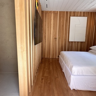 Step into your serene bedroom featuring warm wood panels, crisp linens, and an elegant ensuite with glass shower.