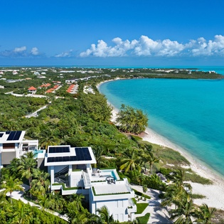Stunning beachfront luxury villas showcase modern architecture amid tropical paradise with pristine white sand and turquoise waters.