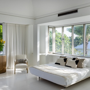 Unwind in your serene white bedroom with garden views, modern furnishings, and refreshing air conditioning for perfect comfort.