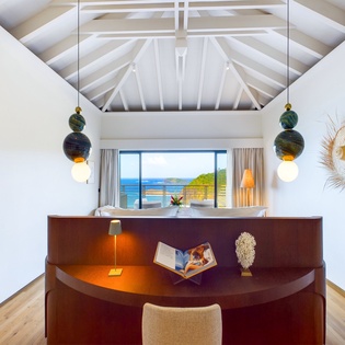 Your peaceful writing nook features a curved wooden desk and stunning ocean views through panoramic windows.