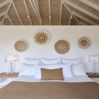 Retreat to crisp white linens and natural textures under soaring vaulted ceilings that evoke a breezy, coastal sanctuary.