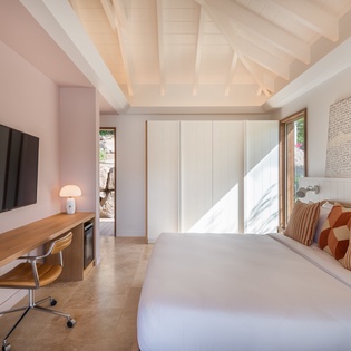 Your serene bedroom features exposed beams, crisp linens, and warm wood accents bathed in natural light.