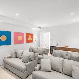 Sink into plush gray sofas surrounded by vibrant geometric art in your spacious, light-filled living area with soaring ceilings.