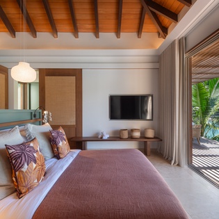 Unwind in your serene tropical bedroom where warm wood meets contemporary comfort, opening to your private terrace.