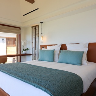 Sink into crisp white linens and ocean-inspired accents in your serene bedroom, where pendant lighting and warm wood create the perfect retreat.