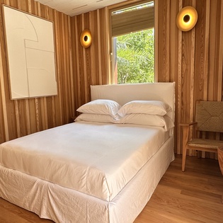 Sink into crisp linens surrounded by warm wood walls in your cozy retreat, where natural light and modern comfort create the perfect sanctuary.