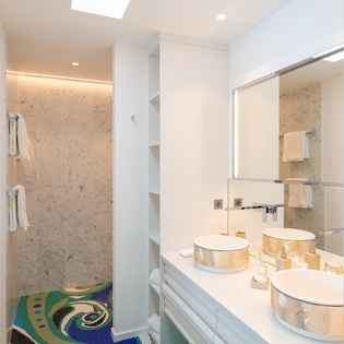 Your luxurious bathroom features dual vessel sinks, elegant marble accents, and a spacious shower with natural skylight.
