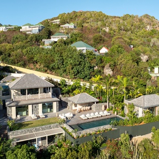 Luxurious hillside villa with private pool nestled in lush tropical landscape, offering panoramic views and ultimate island privacy.