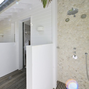 Refresh in your private outdoor shower with rainfall head and tropical palm views surrounding this luxurious open-air retreat.