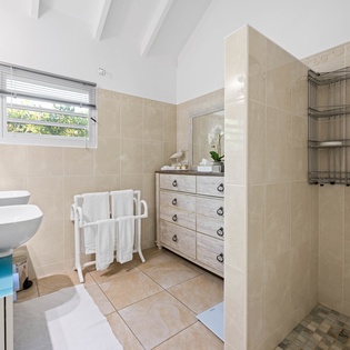 Your elegant bathroom features dual sinks, a spacious walk-in shower, and soft natural light creating a spa-like retreat.