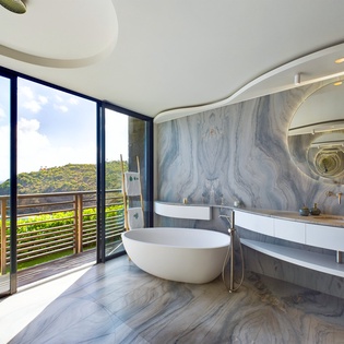 Indulge in your private spa sanctuary with a sculptural soaking tub and stunning ocean views through floor-to-ceiling windows.