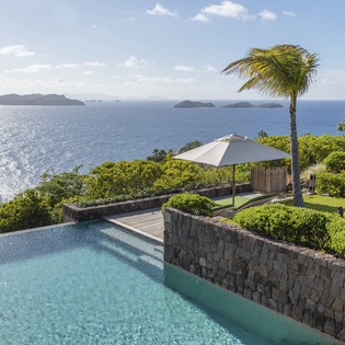 Stunning infinity pool overlooking crystal-clear Caribbean waters with tropical islands dotting the horizon.