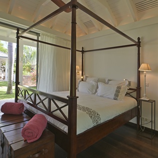 Drift off in your elegant four-poster bed with tropical garden views just beyond your private terrace.
