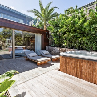 Soak in your private hot tub surrounded by lush tropical gardens, then unwind on sleek loungers in this serene outdoor sanctuary.