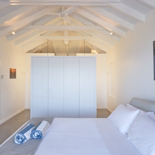 Rest beneath stunning exposed beams in your serene bedroom, where crisp linens and thoughtful artwork create the perfect retreat.