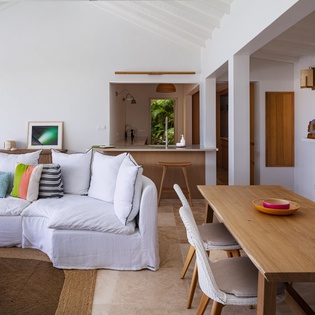 Sink into plush cushions in your bright living space, where warm wood tones and tropical breezes flow through open archways, creating your perfect island sanctuary.