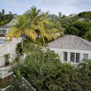 Tropical property nestled in lush hillside with pool terrace and multiple pavilions surrounded by swaying palms.