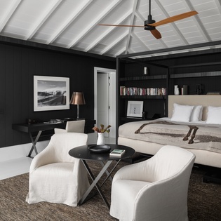 Unwind in your elegant master suite with soaring vaulted ceilings, plush seating area, and sophisticated black-and-white design creating the perfect retreat.