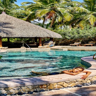 Slip into this tropical paradise where crystal-clear waters meet swaying palms, creating your perfect poolside sanctuary.