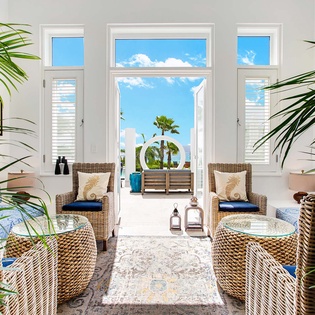Settle into woven coastal elegance where natural textures meet bright, airy comfort—your serene retreat with palm-framed views and ocean breezes just beyond the door.