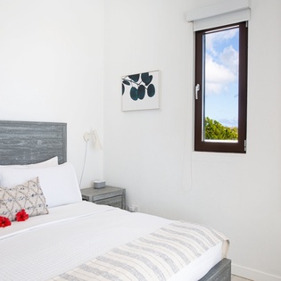 Wake up refreshed in your serene bedroom, where crisp linens and coastal views through the window invite restful mornings and peaceful tropical breezes.