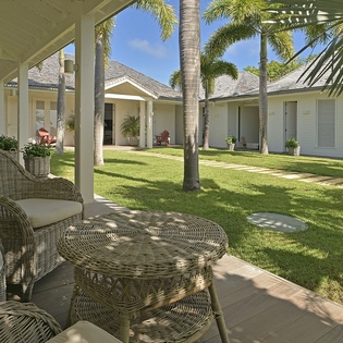 Relax on your private covered terrace with wicker seating overlooking lush tropical gardens and swaying palm trees.
