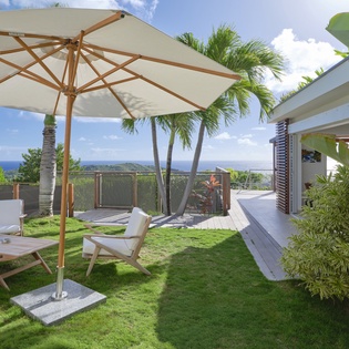 Unwind in your private tropical garden with comfortable lounge chairs under shade, surrounded by swaying palms and ocean views.