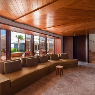Unwind in your spacious living room where rich wood ceilings and floor-to-ceiling windows frame stunning sea views, inviting the tropical breeze inside.