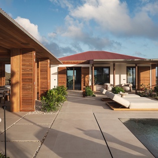 Modern luxury villa featuring elegant outdoor living with private pool and ocean views beyond tropical landscaping.