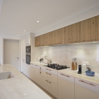 Your sleek modern kitchen combines warm wood with pristine counters, perfect for preparing memorable meals during your stay.