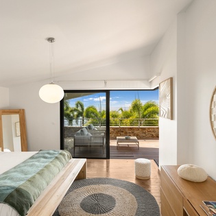 Wake up to tropical views from your serene bedroom sanctuary, where modern comfort meets coastal elegance through expansive glass doors.