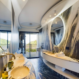 Indulge in your own marble sanctuary with dramatic curved design, golden accents, and serene nature views.