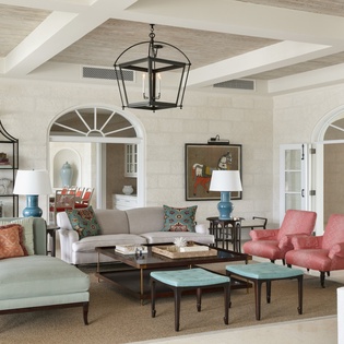 Sink into plush seating beneath soaring beamed ceilings, where colorful accent chairs and coastal-inspired decor create your perfect space to unwind in style.