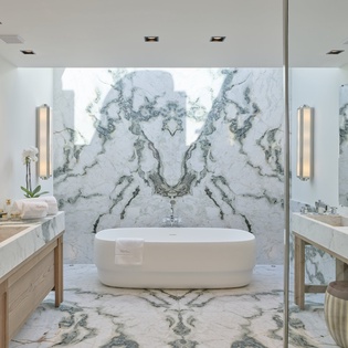 Indulge in pure luxury with this stunning marble bathroom featuring a freestanding soaking tub and elegant dual vanities.